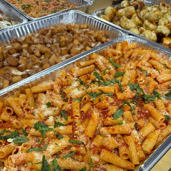 JD's Pazzo Pizza catering trays with rigatoni, roasted potatoes, and garlic knots.