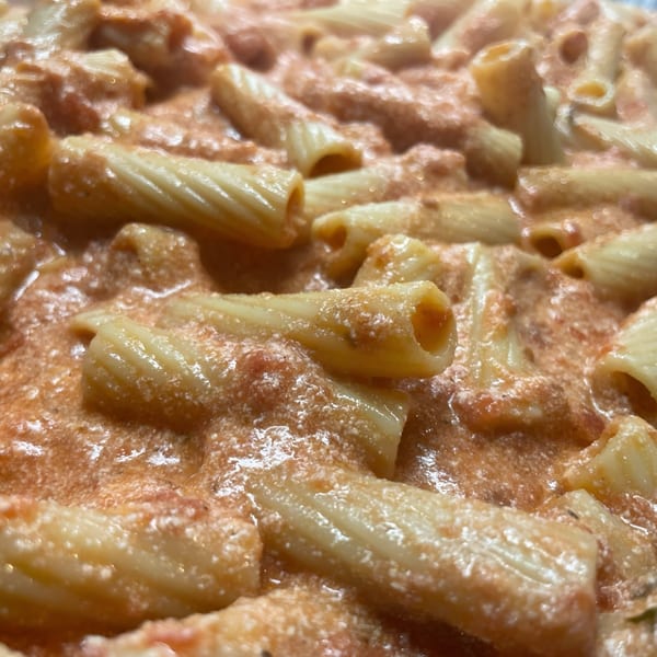 Close-up of rigatoni pasta coated in a creamy pink sauce, ready to be served.