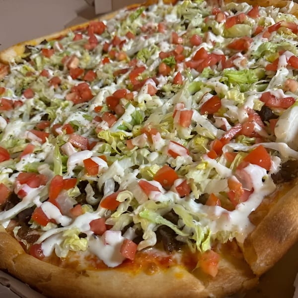 JD's Pazzo Pizza's taco pizza, topped with shredded lettuce, diced tomatoes, and white sauce.